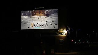 A photography of a Guinness Christmas billboard advert showing pint-like footprints in snow