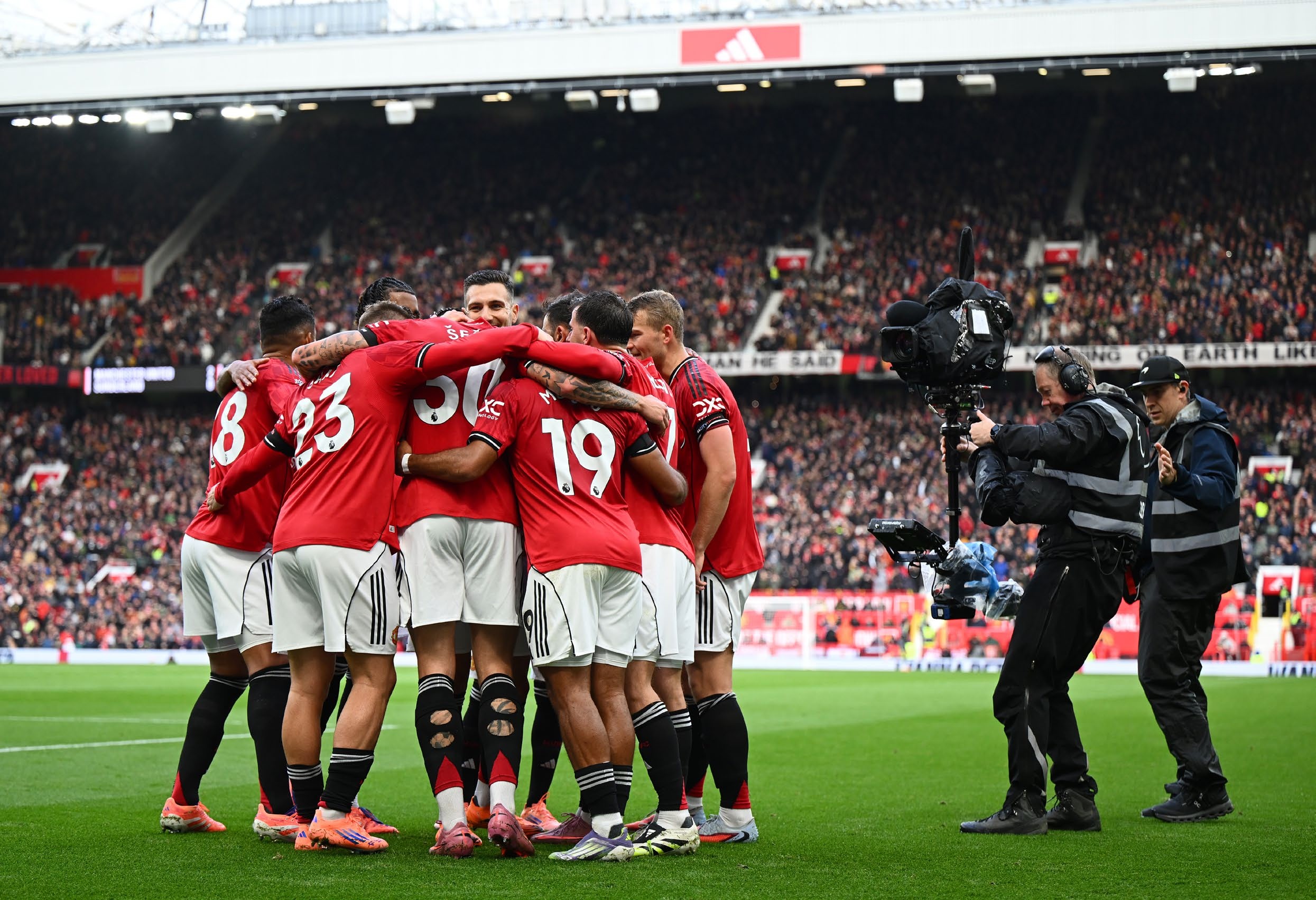 Manchester United players huddle in celebration.