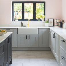Pink painted kitchen with grey kitchen cabinets, white countertops, and a tiled floor