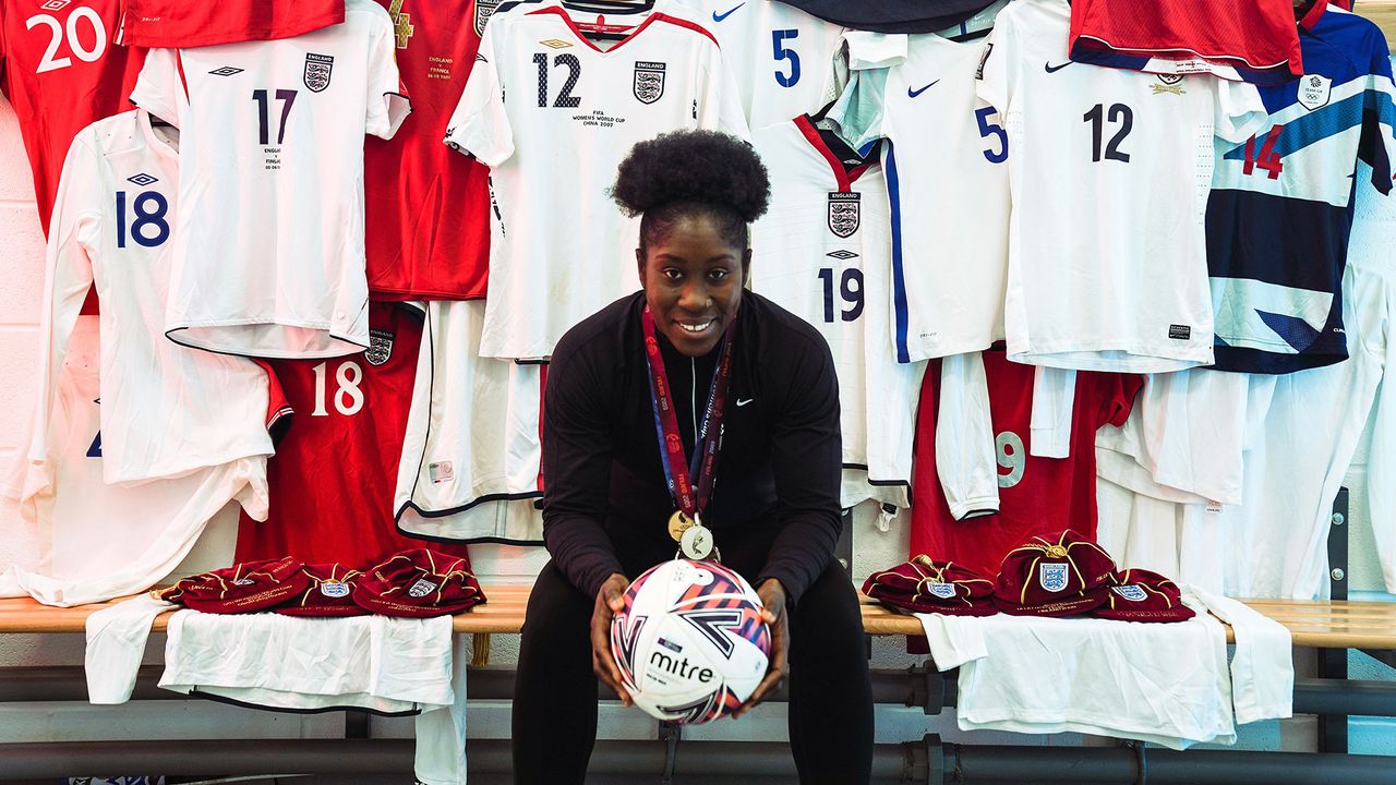 Footballer Anita Asante in front of a selection of football shirts