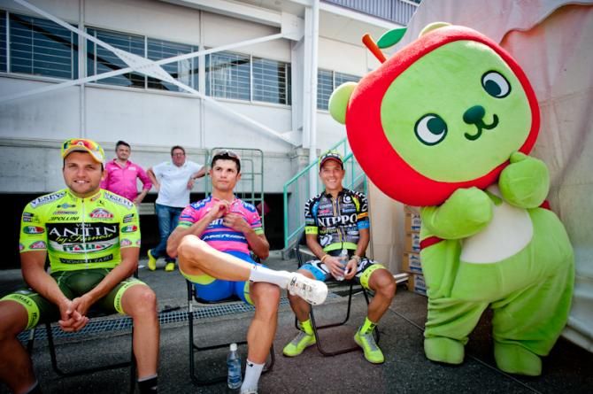 Winners awaiting the award ceremony with a mascot of the city at the Tour of Japan