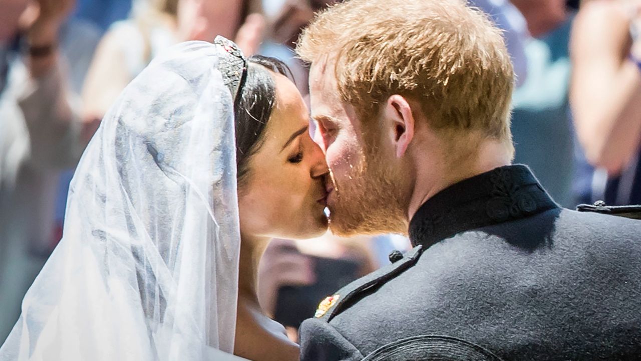 Britain&#039;s Prince Harry, Duke of Sussex kisses his wife Meghan, Duchess of Sussex as they leave from the West Door of St George&#039;s Chapel, Windsor Castle, in Windsor, on May 19, 2018 after their wedding ceremony.