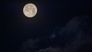 the full moon shines bright in a dark night sky