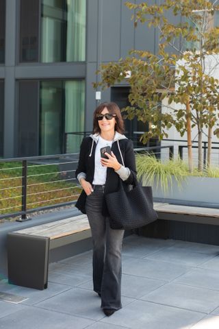 A former Nordstrom buyer wearing a black blazer over a gray hoodie and white tee.