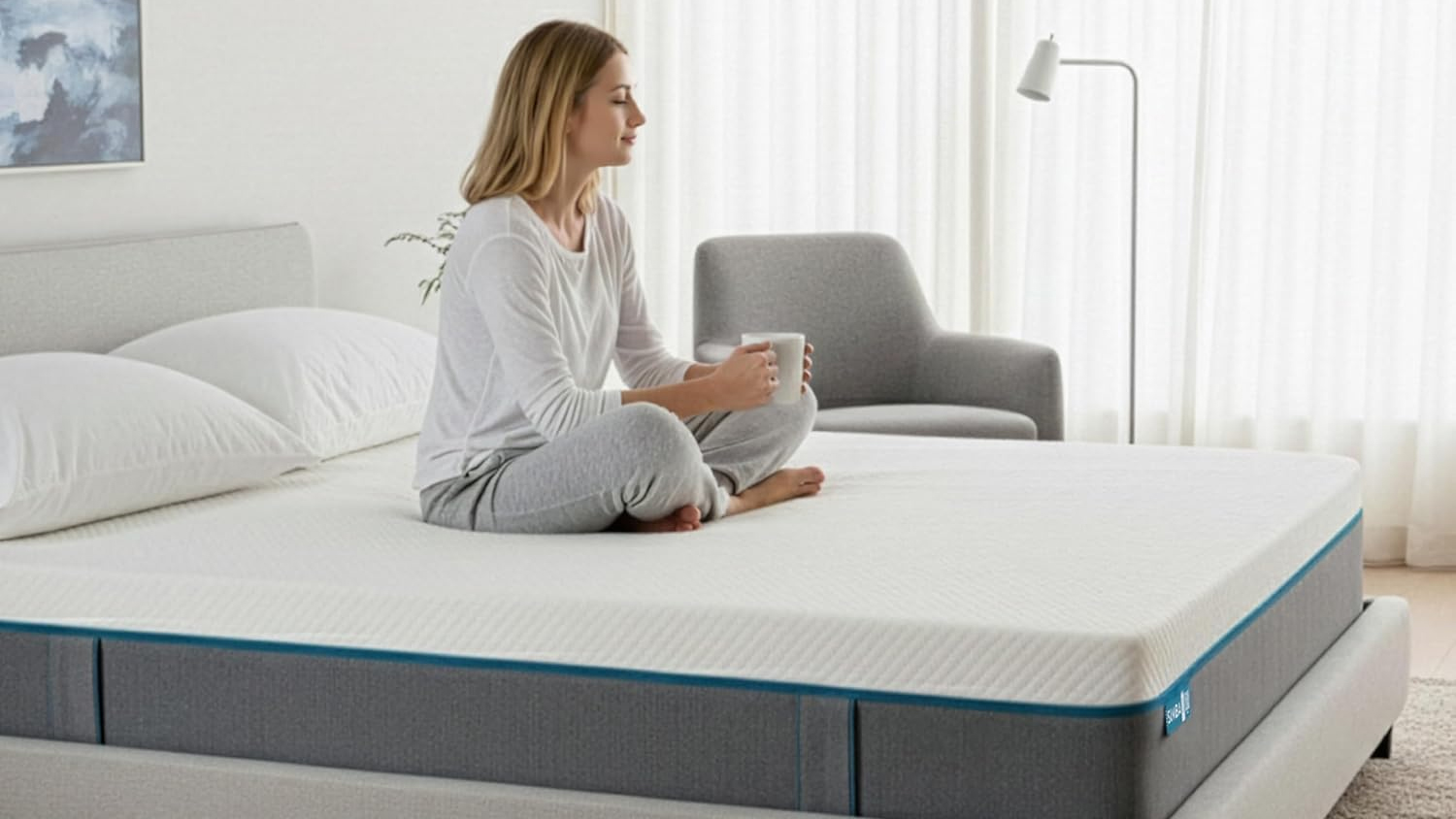 A woman with blonde hair sits peacefully on the Simba Simbatex Cool Mattress with her eyes closed as she holds a cup of warm tea