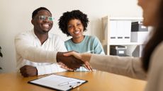 Happy couple shaking hands with financial advisor in office