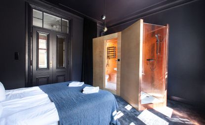 Black walled guestroom with wooden bathroom stall