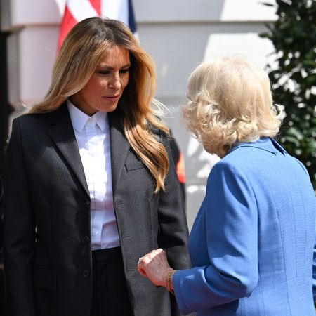 Melania Trump talking to Queen Camilla in front of flags