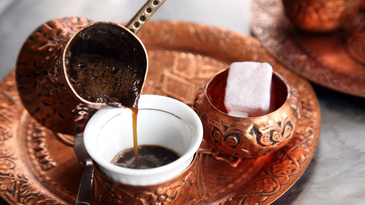 Turkish coffee being made using copper tools with a Turkish delight in the background