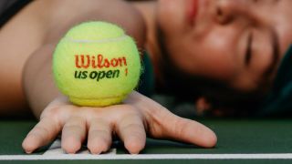 Woman sleeping with her arm outstretch and a Wilson tennis ball in her hand