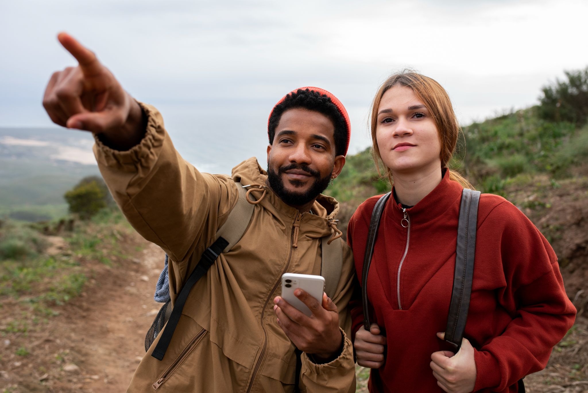 Two people on a hike, one pointing into the distance holding a phone