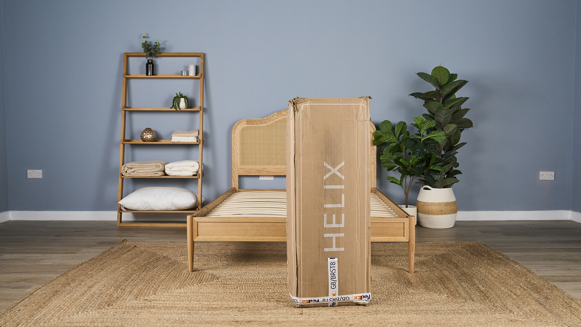 The Helix Dawn Mattress in a compact Helix box, in front of a bed frame as we prepare to unbox it