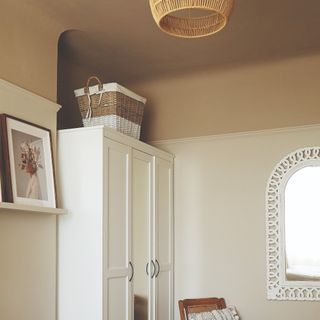 A bedroom with a light brown-painted ceiling taken down to the picture rail on the walls