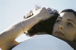 Young woman embracing man, looking away