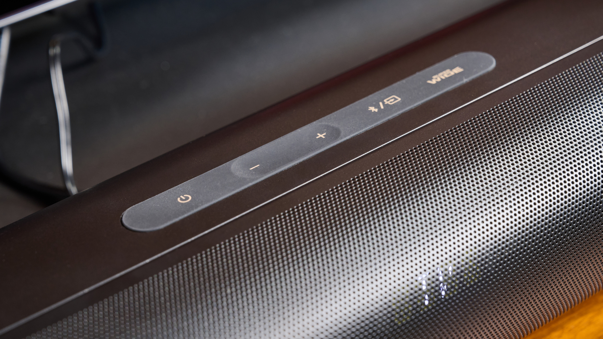 the creative stage pro soundbar and subwoofer, a super-budget home cinema system with 2.1 channels and a remote control photographed on a wooden tv stand with a TV behind