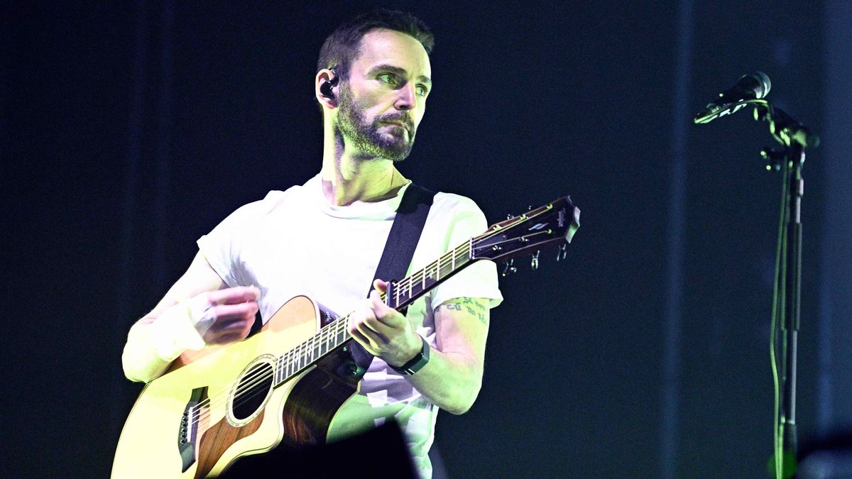 Johnny McDaid performs on stage playing a Taylor acoustic guitar