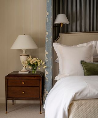 neutral bedroom with wooden nightstand and white bedding