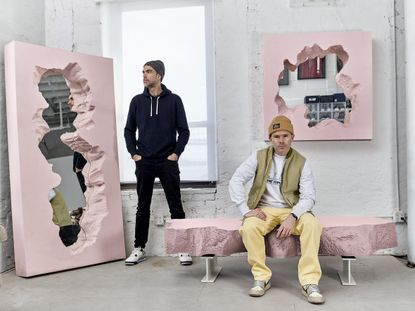 In their New York studio, designer Alex Mustonen and Daniel Arsham pose with the pink furniture collection they designed for Gufram, comprising two mirrors and a bench 