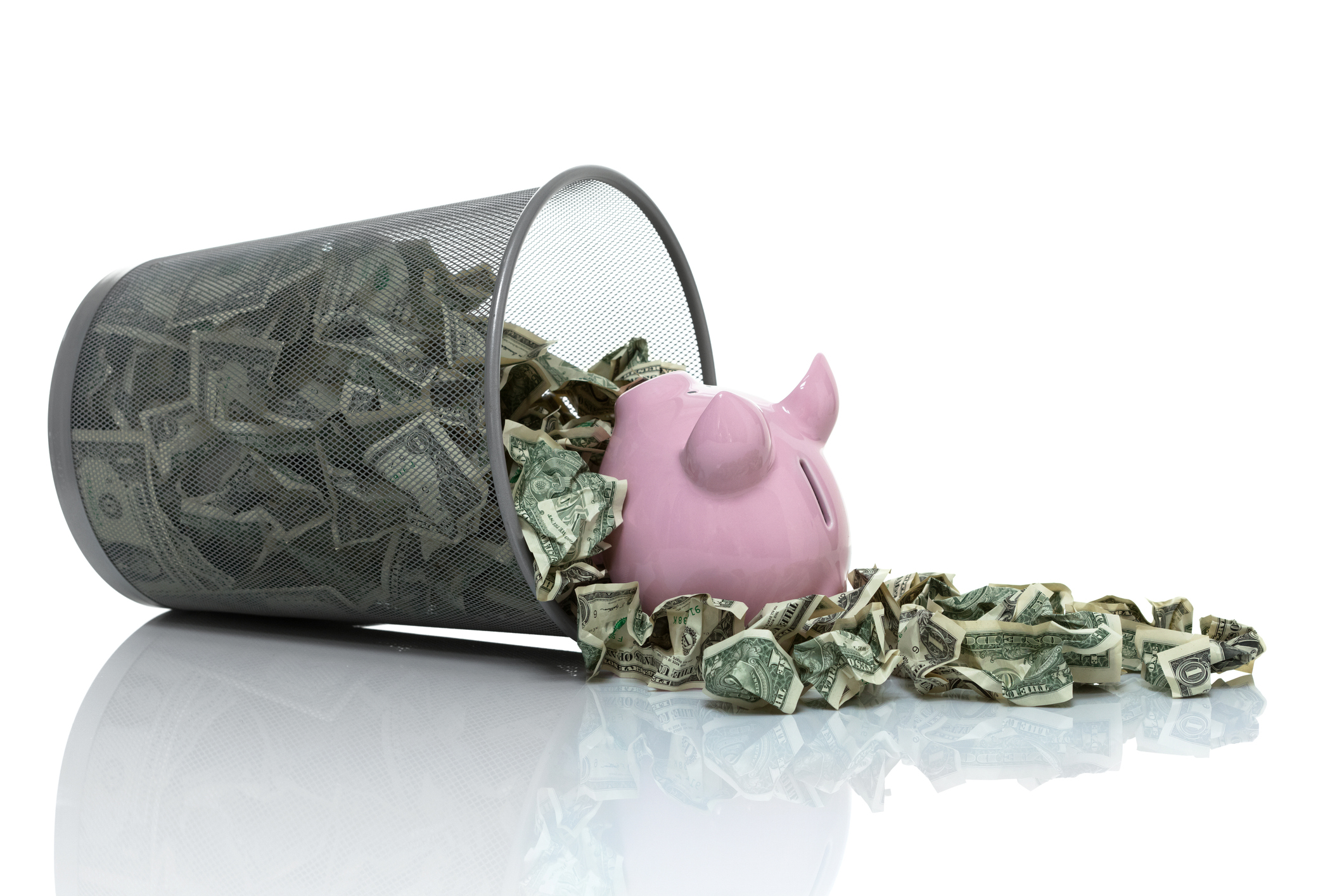 Garbage can full of money tipped on its side wit piggy bank in it
