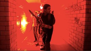 Mireille Enos and Brad Pitt walking down a hallway with a flare in World War Z.