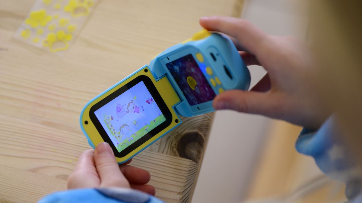 Cheap blue kids camera on a table with screen flipped out and games being played