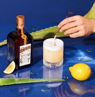 Cointreau new bottle and cocktail against blue background and lemon
