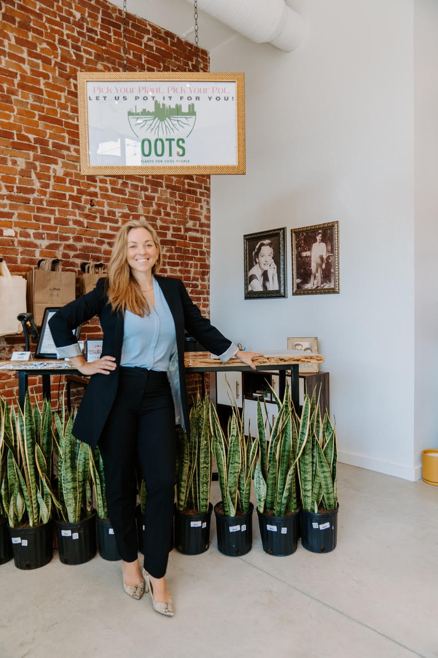 Woman in navy suit stood in office in front of multiple potted snake plants