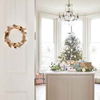 Christmas kitchen decorations, kitchen island with presents and baubles, tree in bay window, LED wreath on door to kitchen