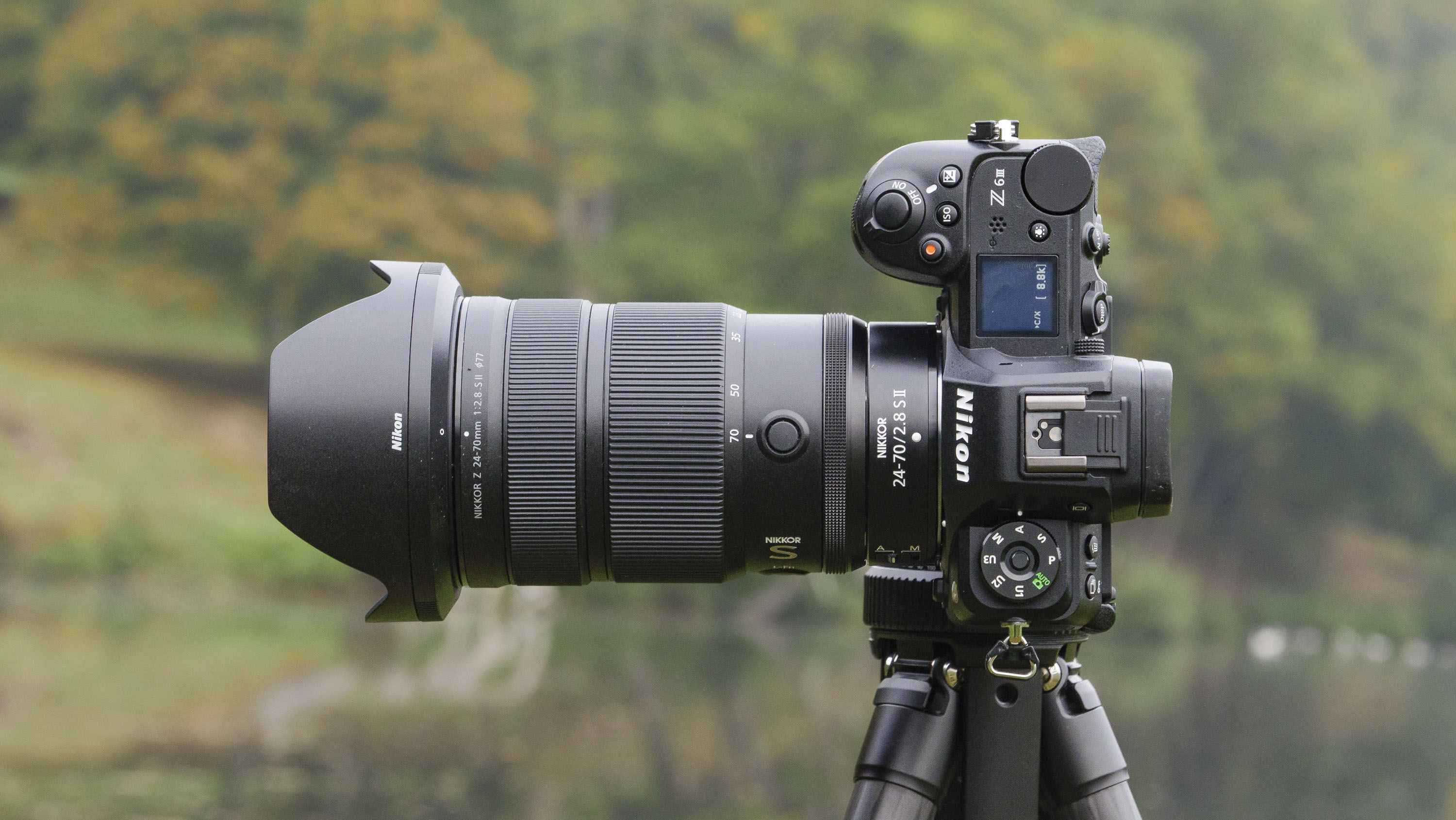 Nikon Z 24-70mm f/2.8 S II lens mounted to a tripod with autumnal lake background