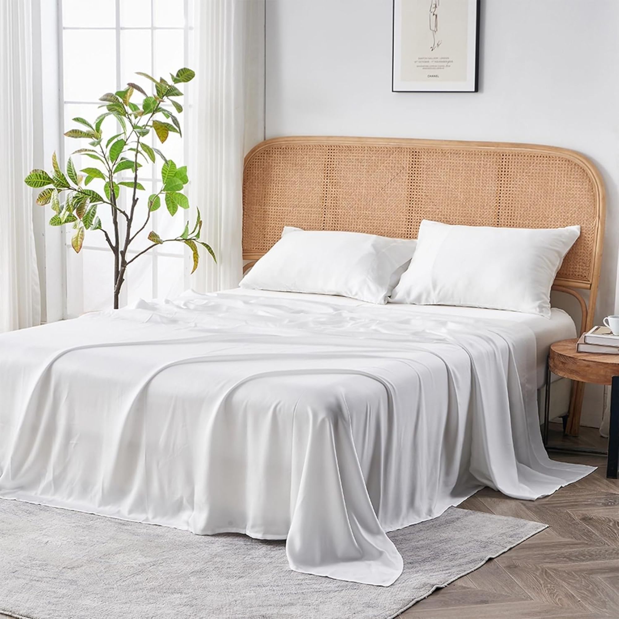 Sijo AiryWeight Tencel Sheet Set shown on a bed with rattan curved headboard in a minimalist bedroom with white walls, grey rug, dark wood flooring, large tree, and large windows with white curtains.