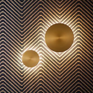 Gold round wall lights on zig-zag wallpaper