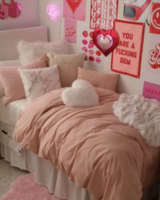 A pink dorm room with wall art and pink decor