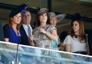 Sarah Ferguson wears a blue dress with a black hat, and stands next to ex-husband Prince Andrew, and daughters Princess Beatrice and Princess Eugenie