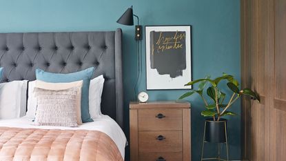 Teal bedroom with grey headboard and pink throw