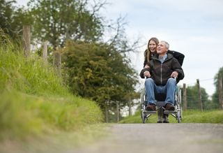 a carer with a man in a wheelchair in the countryside