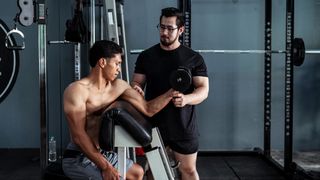 Man performs the one-arm preacher curl biceps exercise with a dumbbell