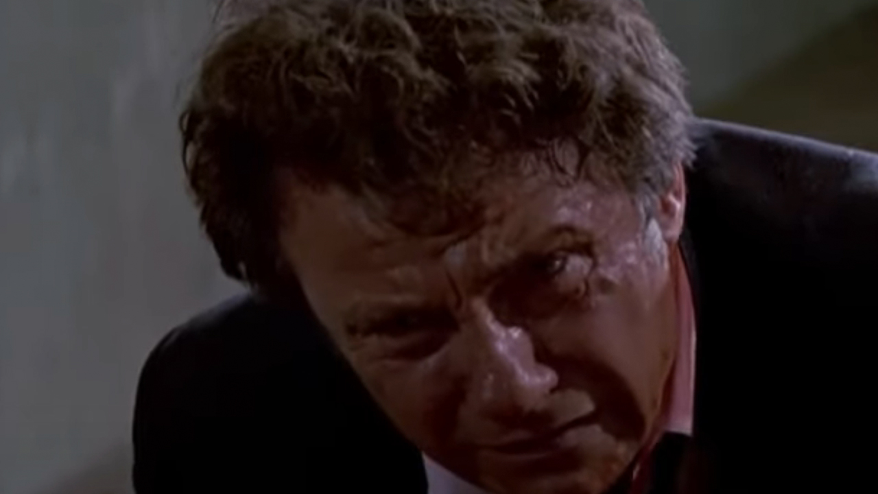 A close up of Harvey Keitel looking like he is in pain at the end of Reservoir Dogs.