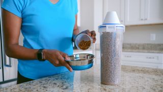 Woman serving food from a pet food container.