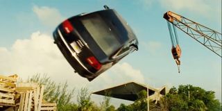 Jason Statham driving a car towards a crane in Transporter 2