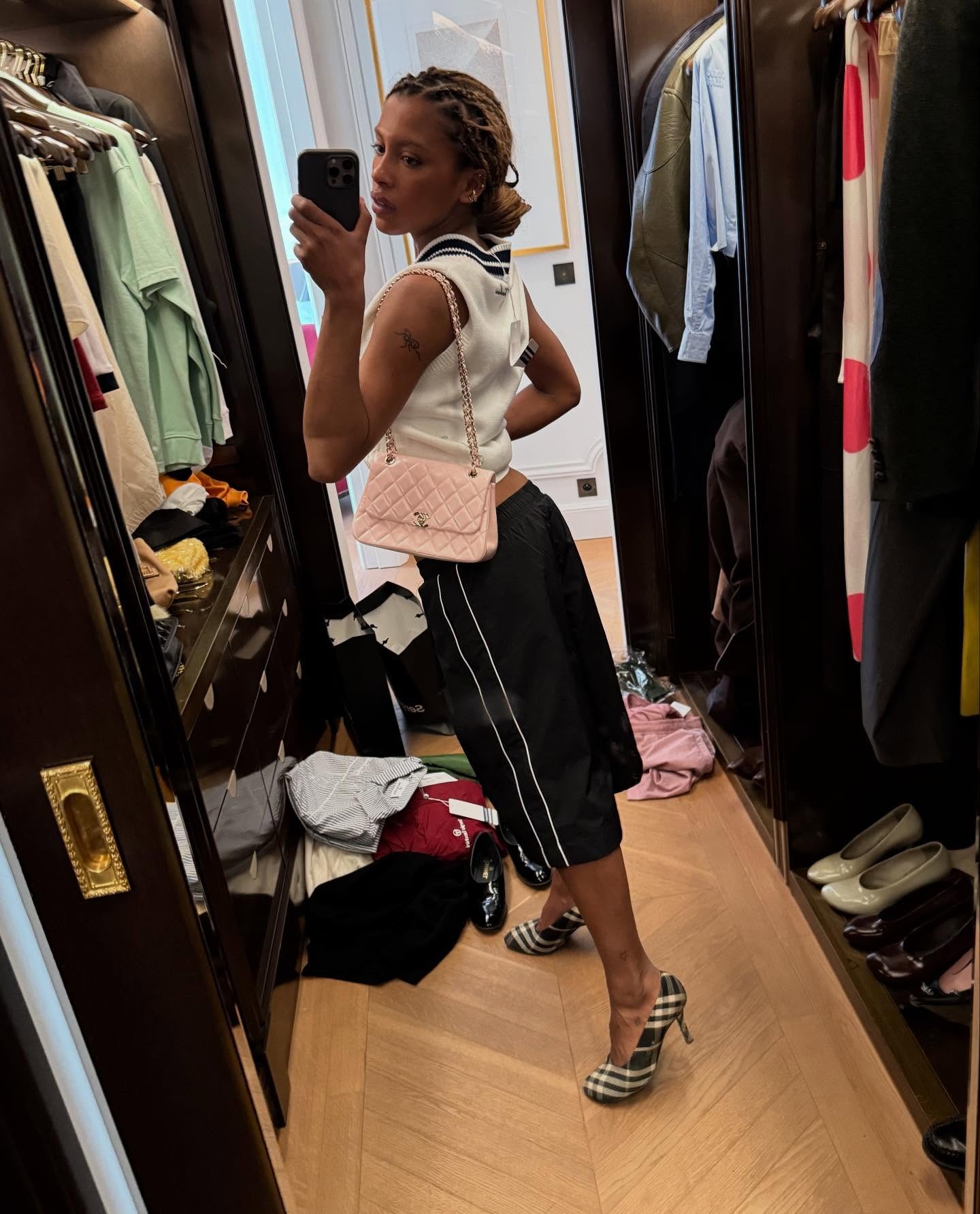 A woman wearing a sporty outfit with a slicked-back bun, taking a mirror selfie