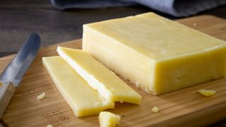 block of cheese on board, partially sliced