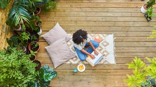 Woman working from home outside in her garden surrounded by plants