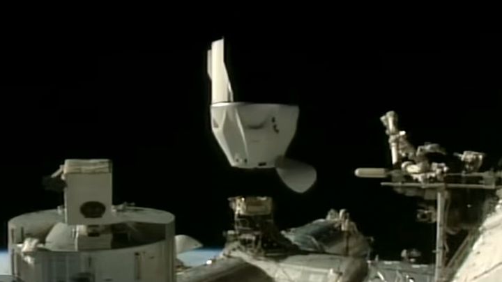 A black and white Dragon capsule undocks from a space station