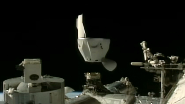 A black and white Dragon capsule undocks from a space station