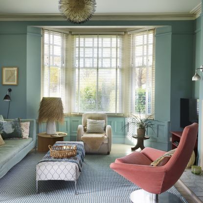 blue living room with pink armchair and a bay window