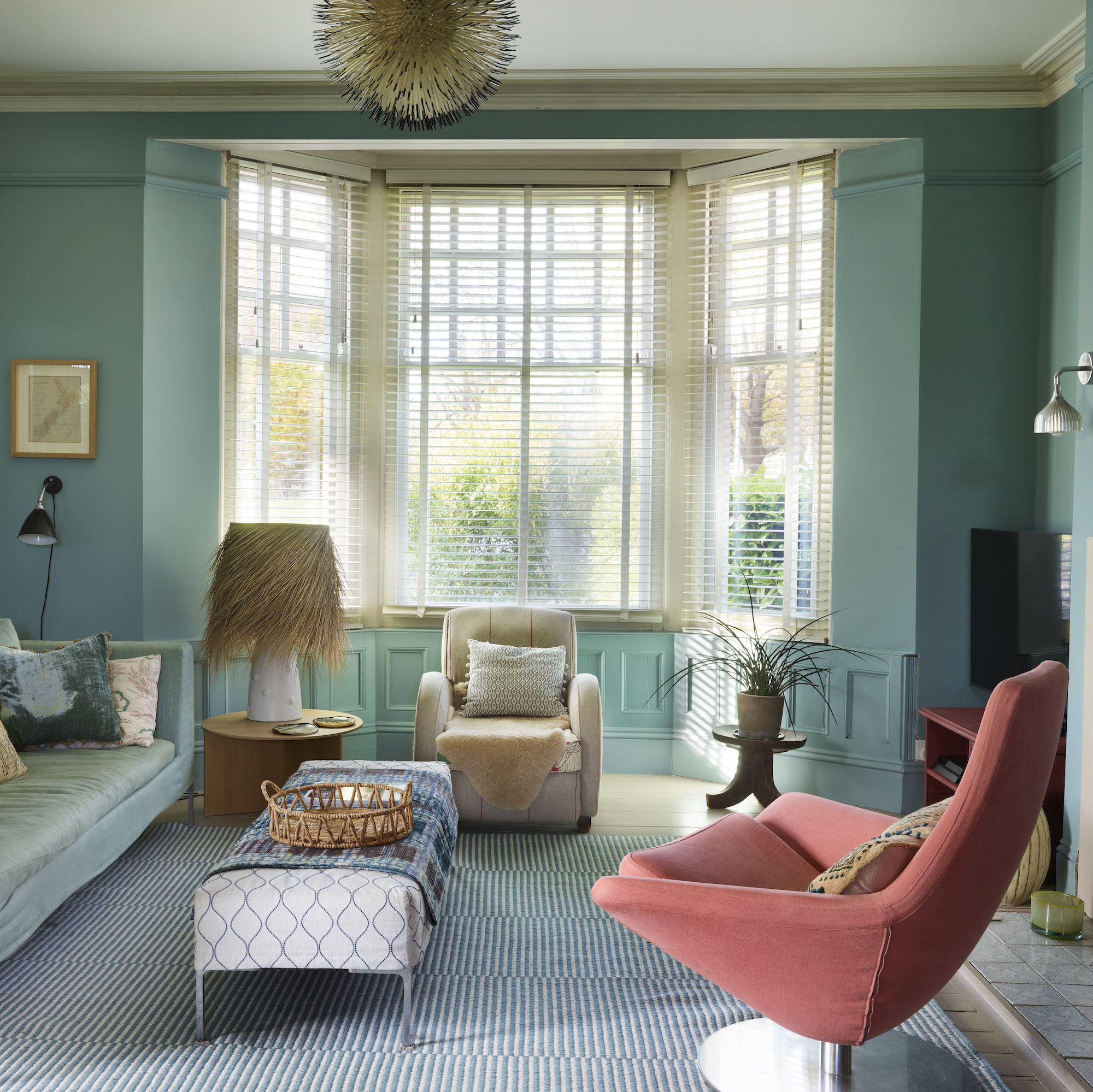 blue living room with pink armchair and a bay window