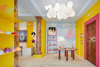 A brightly colored concept-store with yellow walls and pink-shaded furniture displays a selection of table ceramics, sculptures and paintings.