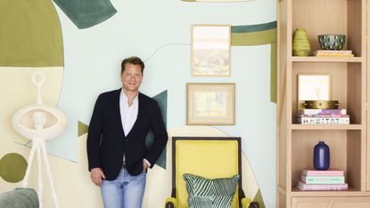 Nathan Turner standing in front of a large mural next to yellow chair and pink bookcase