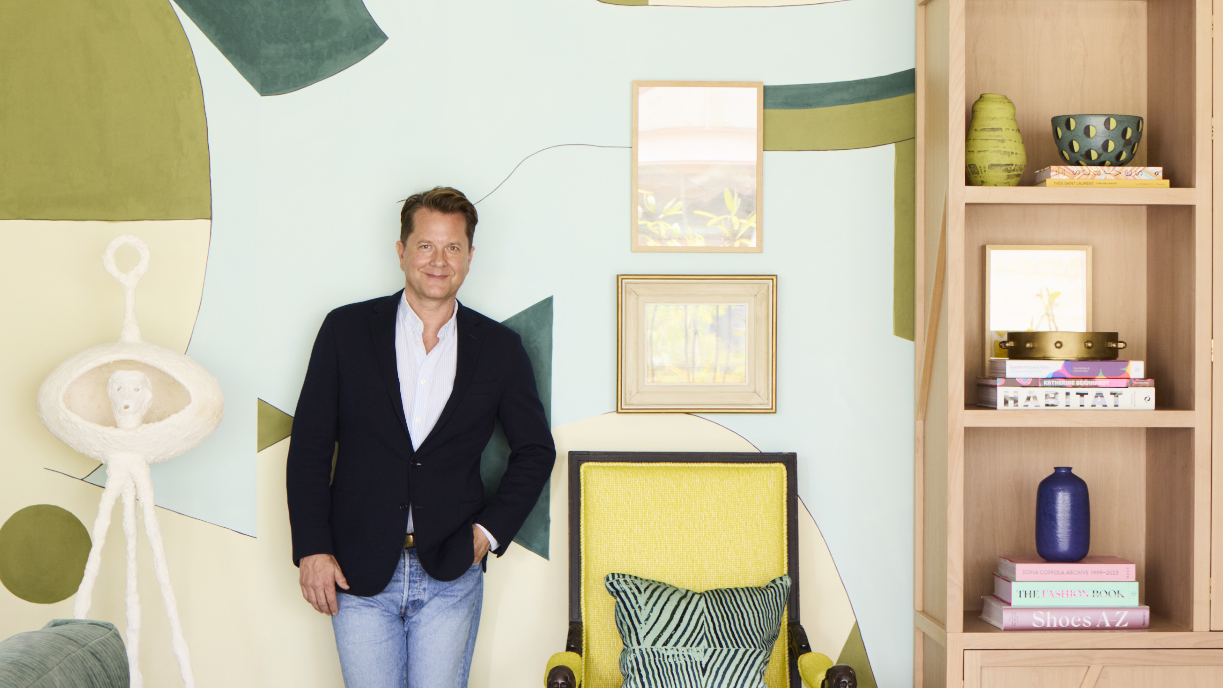 Nathan Turner standing in front of a large mural next to yellow chair and pink bookcase