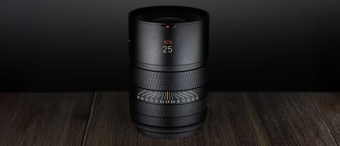 Hasselblad XCD 25V lens, on a wooden table, shot with dramatic light against a dark background